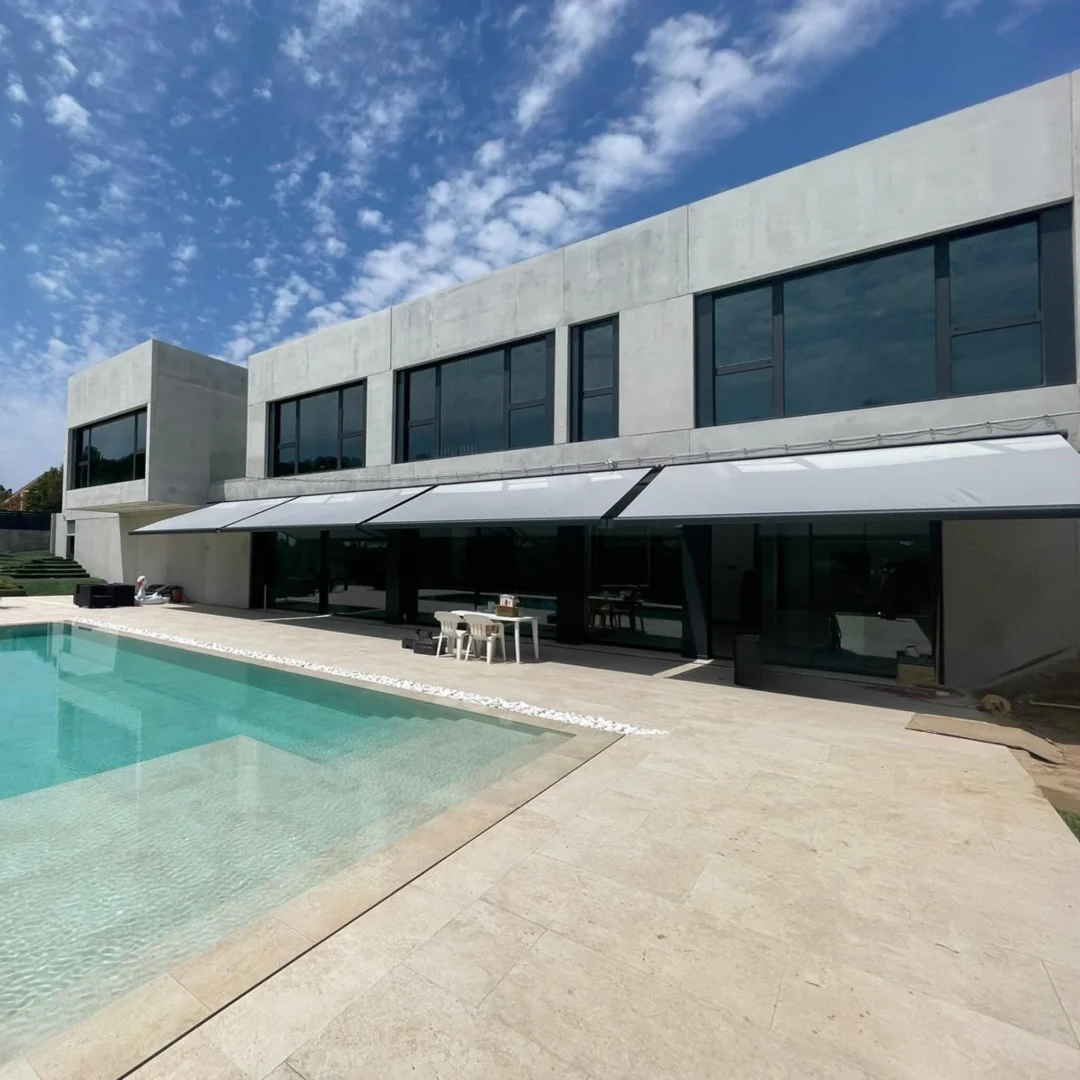 Casa con piscina en día soleado con toldos extensibles